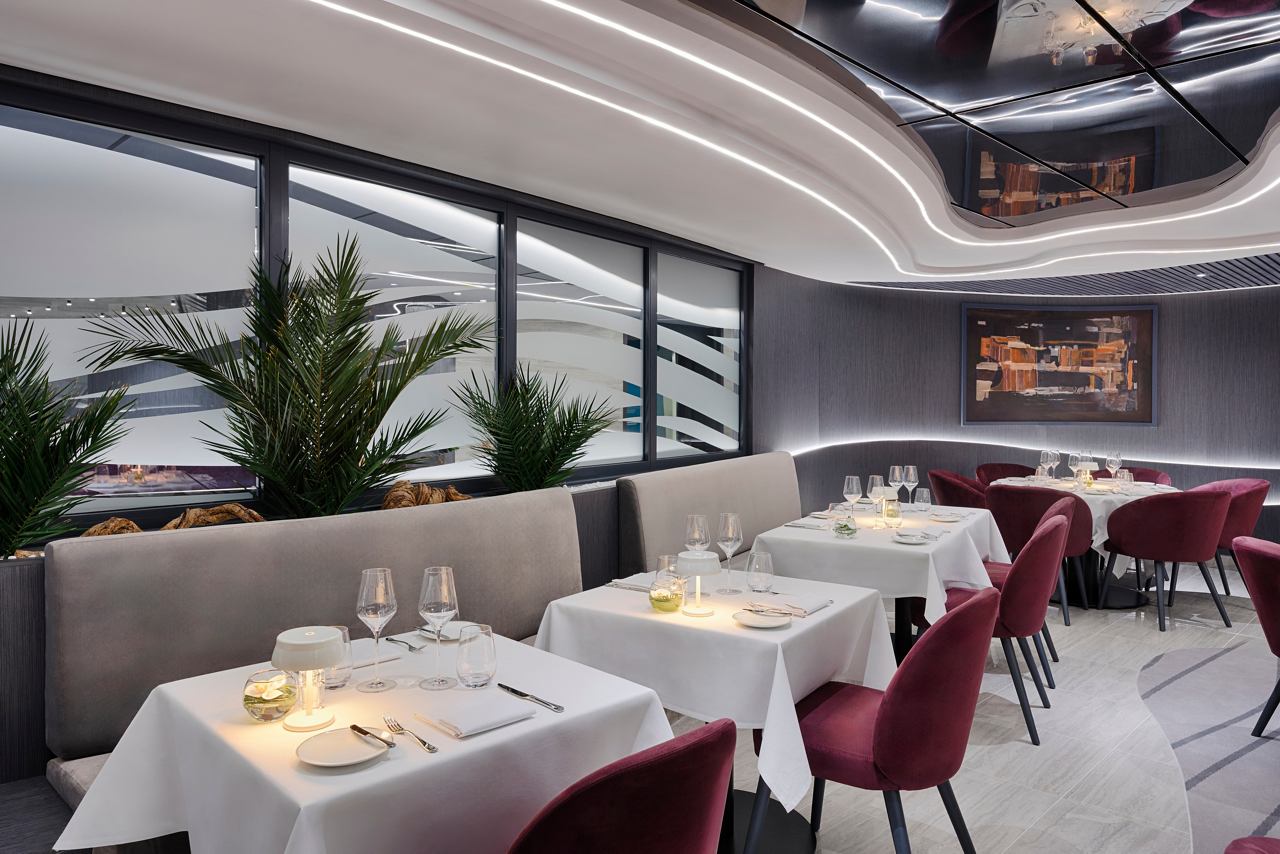 Elegant restaurant with fine tables and green plants, creating a welcoming atmosphere | MSC Cruises