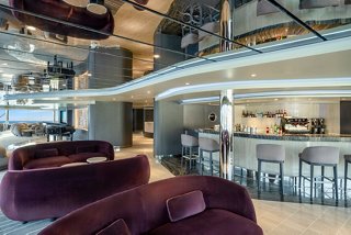 Zona de estar de lujo en el MSC Yacht Club con bar y piano, perfecta para relajarse | MSC Cruceros