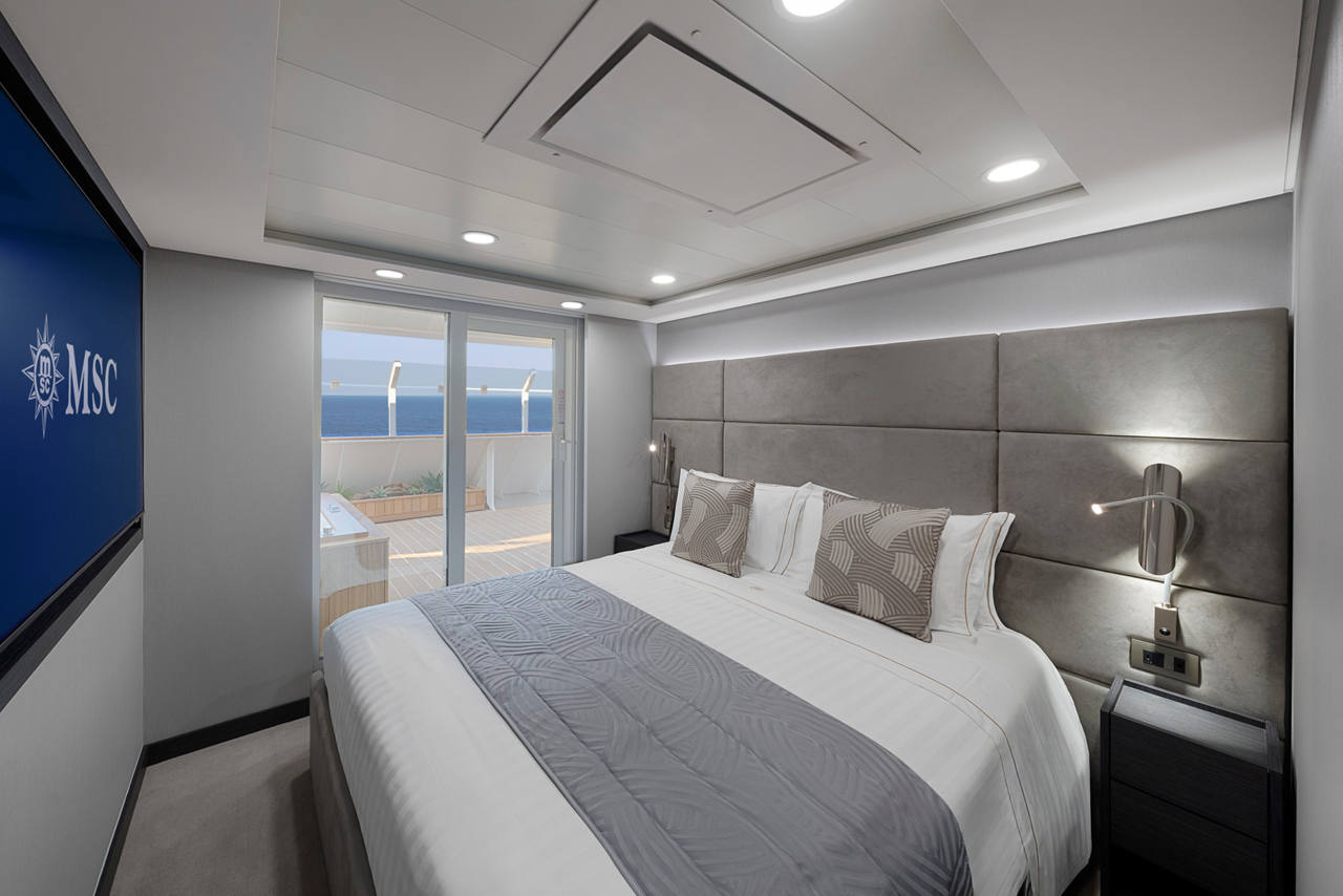 Cabina en el MSC Yacht Club con cama doble y un interior acogedor, que ofrece comodidad y lujo | MSC Cruceros