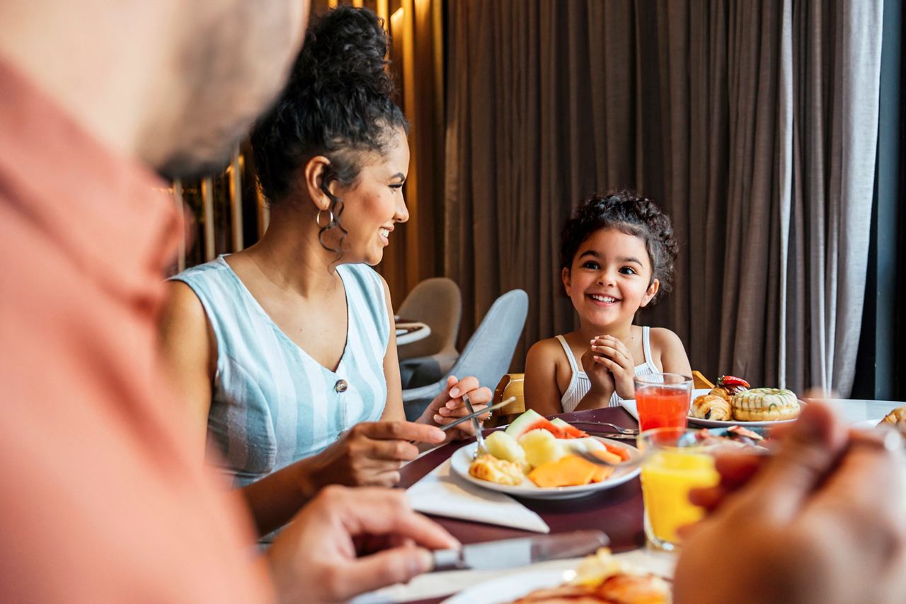 A family enjoys breakfast together, with mother, daughter, and father sharing smiles | MSC Cruises