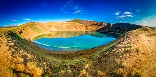 A volcanic crater with a blue lake in Iceland, surrounded by rocky hills | MSC Cruises