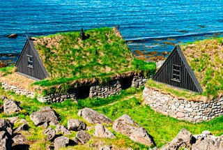 Old fishing cottage with a vegetation-covered roof in Isafjordur, Iceland, against a backdrop of blue sea | MSC Cruises