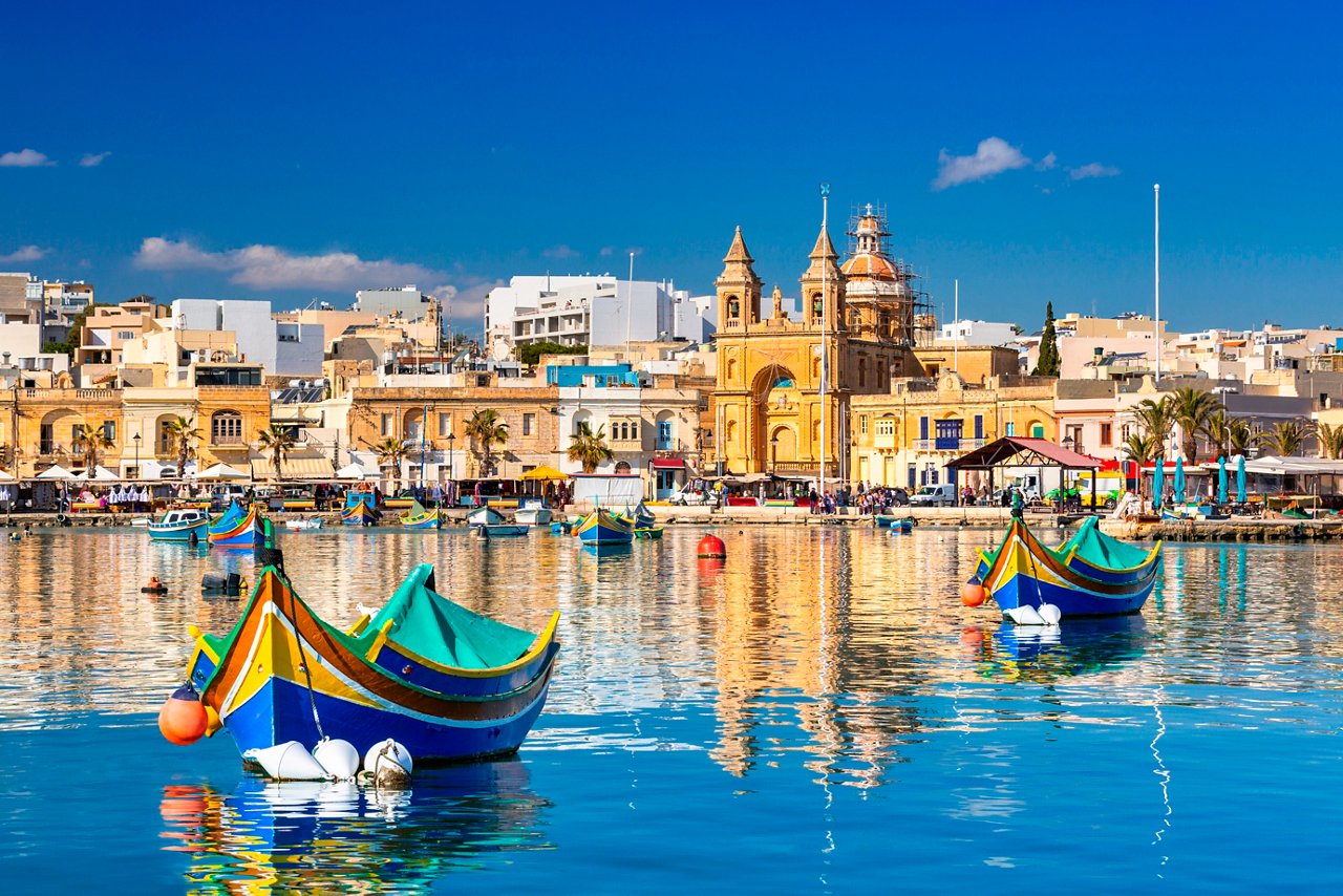 Tranquil harbor scene with colorful boats and beautiful buildings in Malta | MSC Cruises