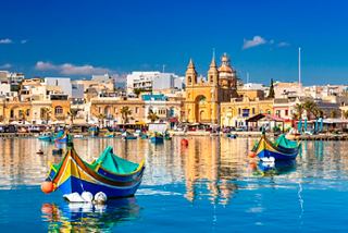 Tranquil harbor scene with colorful boats and beautiful buildings in Malta | MSC Cruises