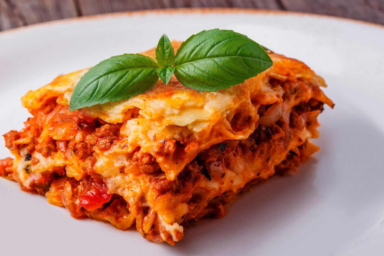 A serving of lasagna garnished with basil on a plate | MSC Cruises