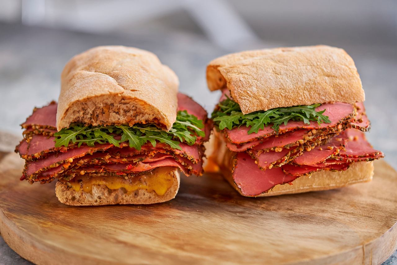 Two sandwiches with pastrami and greens on a wooden board | MSC Cruises