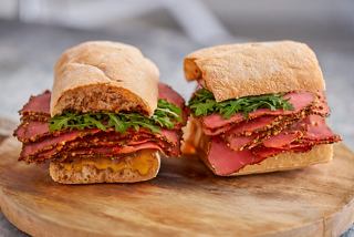 Dos sándwiches con pastrami y ensalada sobre una tabla de madera | MSC Cruceros