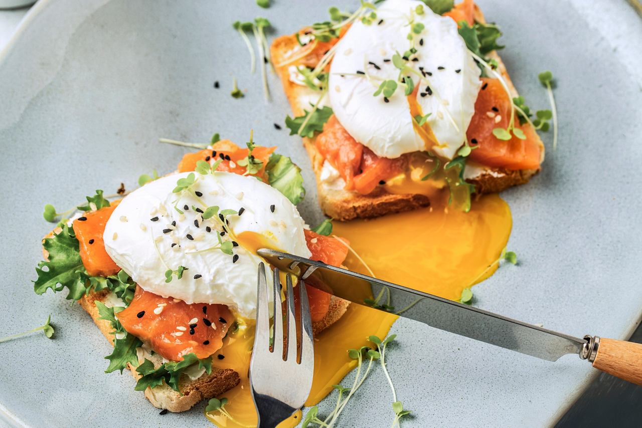 Toast topped with smoked salmon and poached eggs, garnished with fresh herbs | MSC Cruises