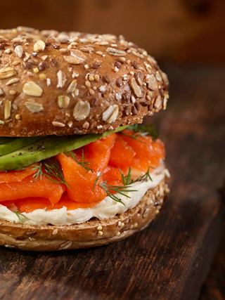Bagel con salmón ahumado, queso crema y verduras, servido sobre una superficie de madera | MSC Cruceros