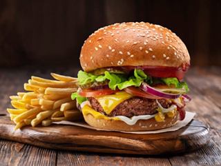 Hamburguesa jugosa con papas fritas sobre una tabla de madera | MSC Cruceros
