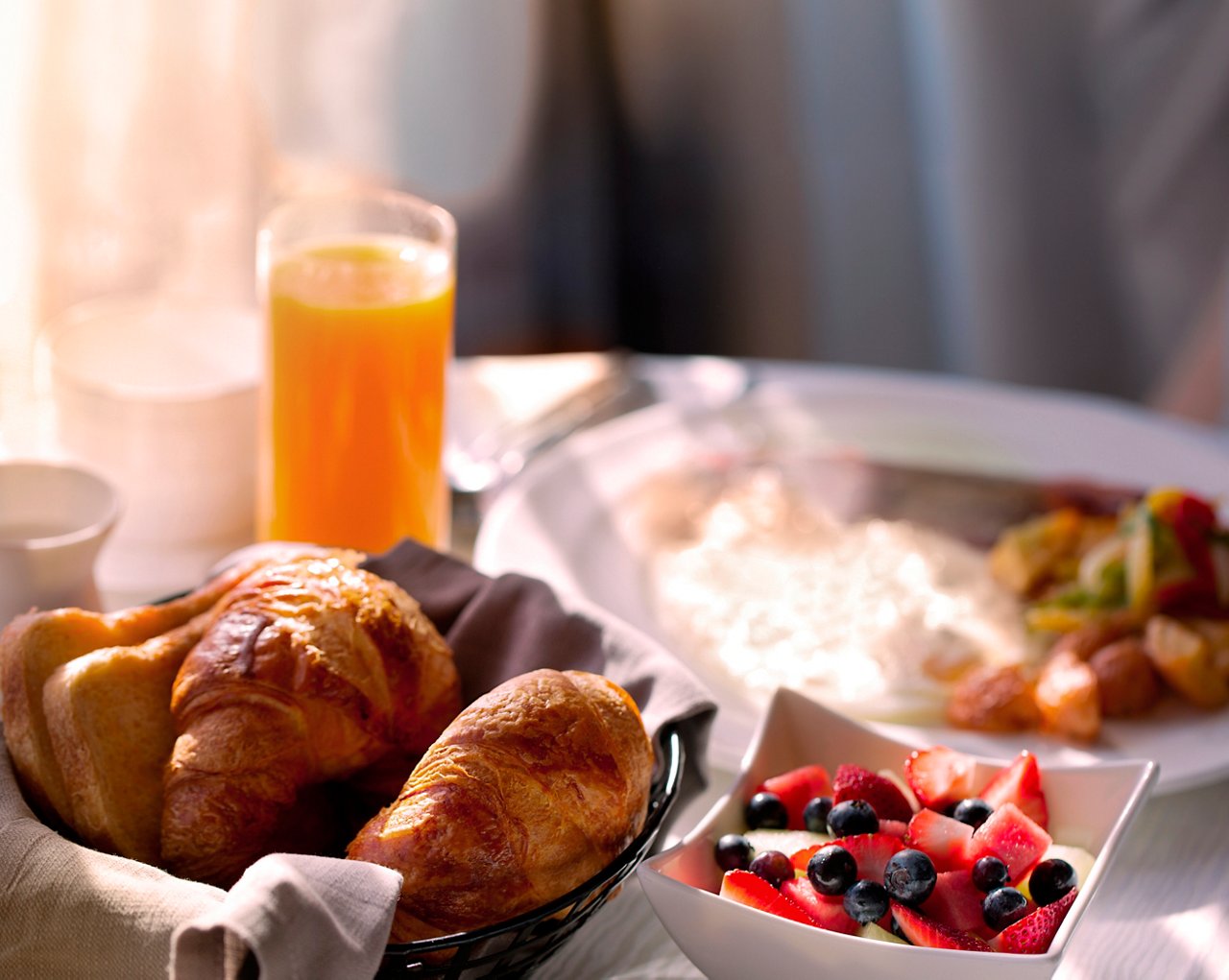 Breakfast featuring croissants, fruit salad, and juice with a sunrise view | MSC Cruises