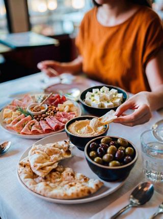 Una bandeja con varios aperitivos, incluyendo hummus y queso, en una mesa acogedora | MSC Cruceros