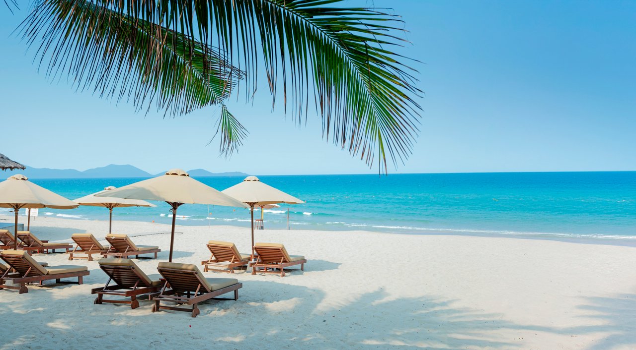 Playa con palmeras y sombrillas, mar azul y cielo en la República Dominicana | MSC Cruceros
