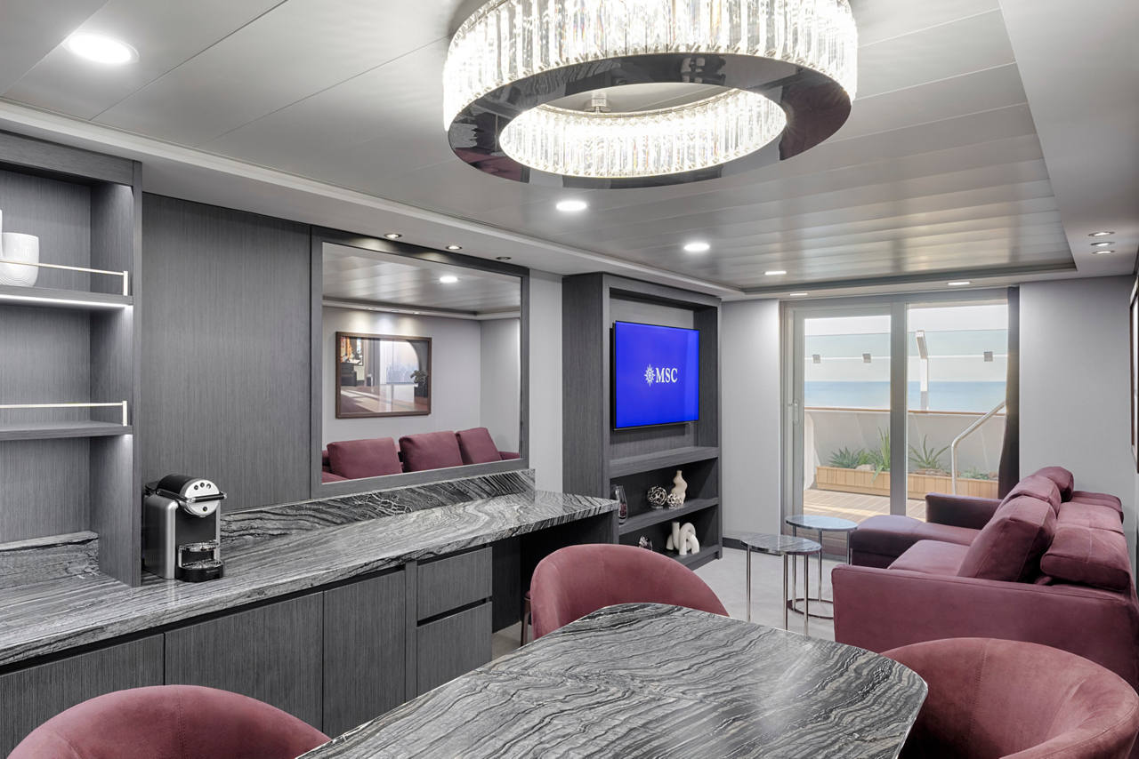 Sala moderna con muebles cómodos y televisión, perfecta para relajarse a bordo del MSC Magnifica | MSC Cruceros