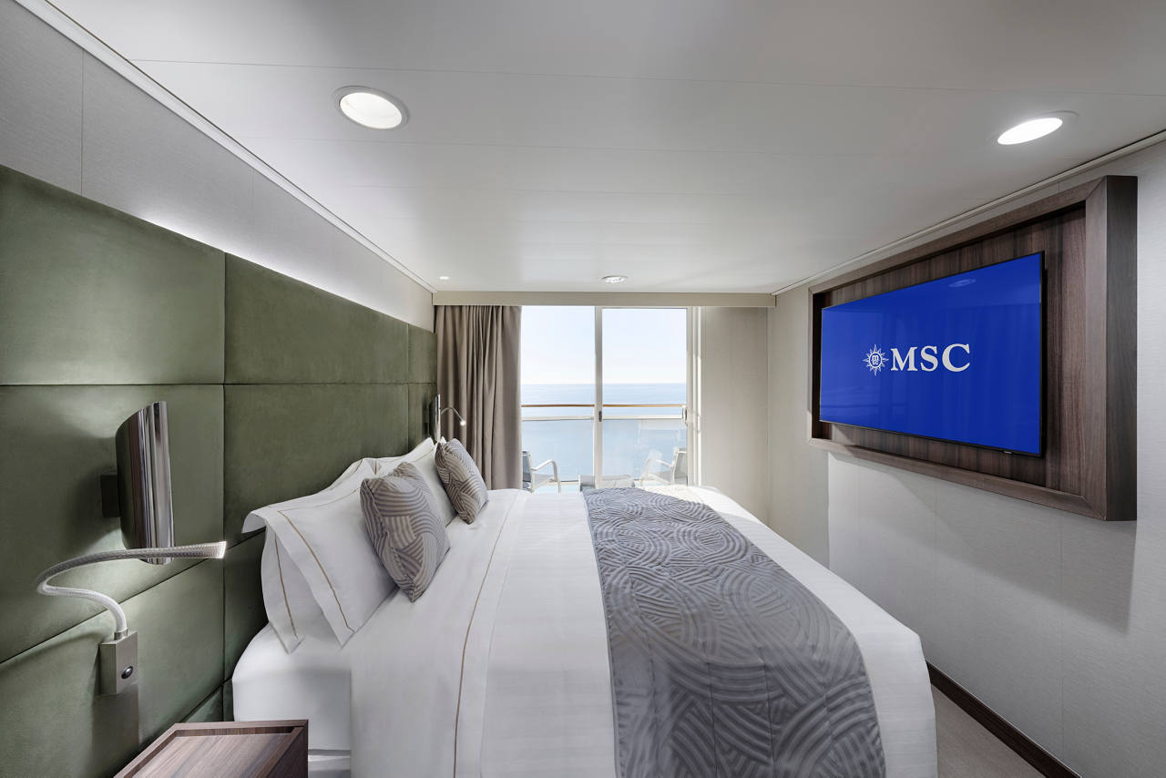 Suite amplia con cama doble, televisor y balcón con vista al mar | MSC Cruises