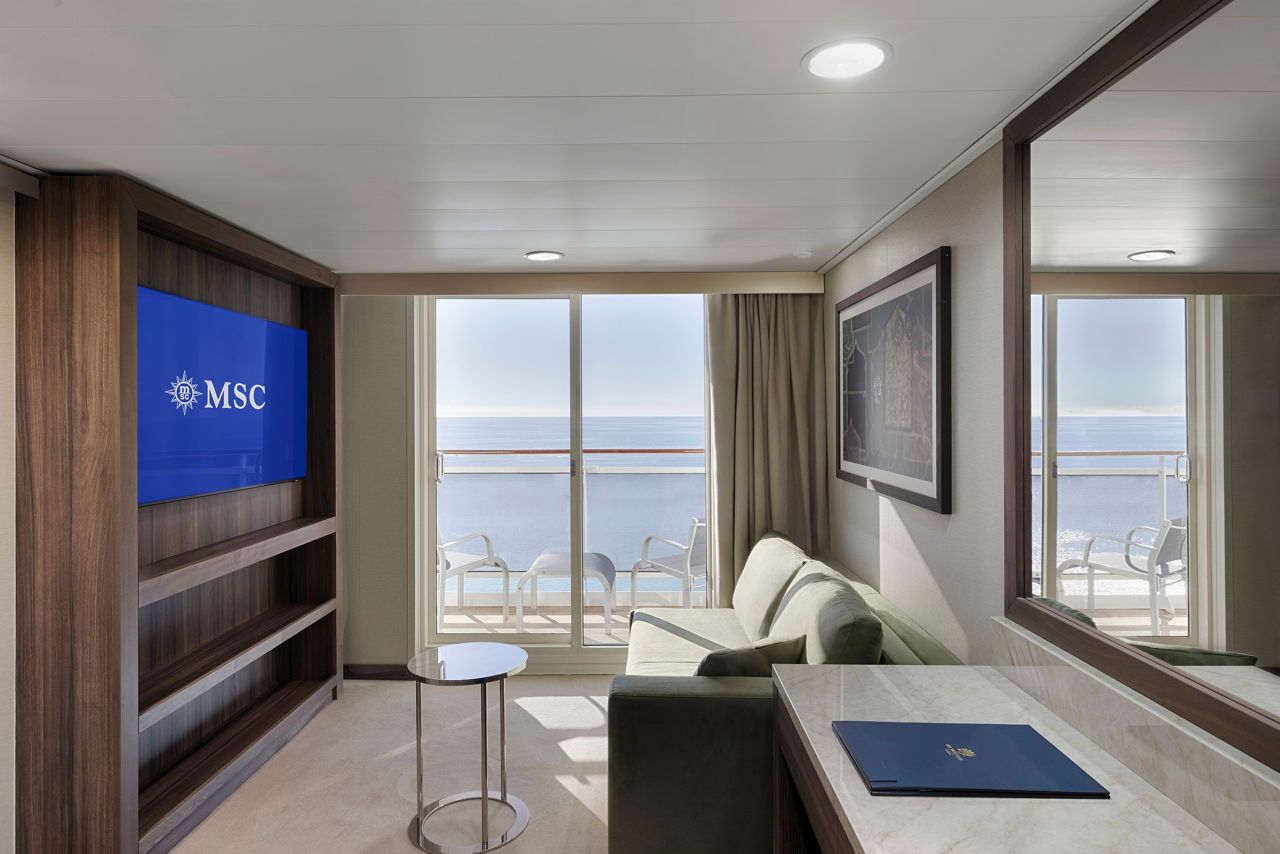 Suite amplia con balcón, vista al mar, televisión y área de estar cómoda | MSC Cruises