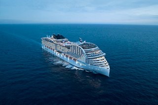 Luftaufnahme des MSC World Europa Schiffs auf See mit Licht am Bug und Schornstein | MSC Cruises