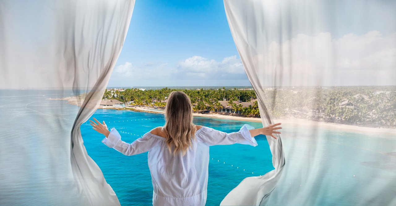 Frau blickt durch Fenster auf karibischen Strand und Vegetation | MSC Cruises