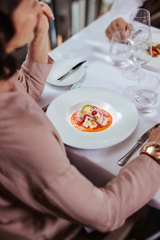 Mujer sirviendo plato principal con carne en el restaurante MSC Yacht Club | MSC Cruceros