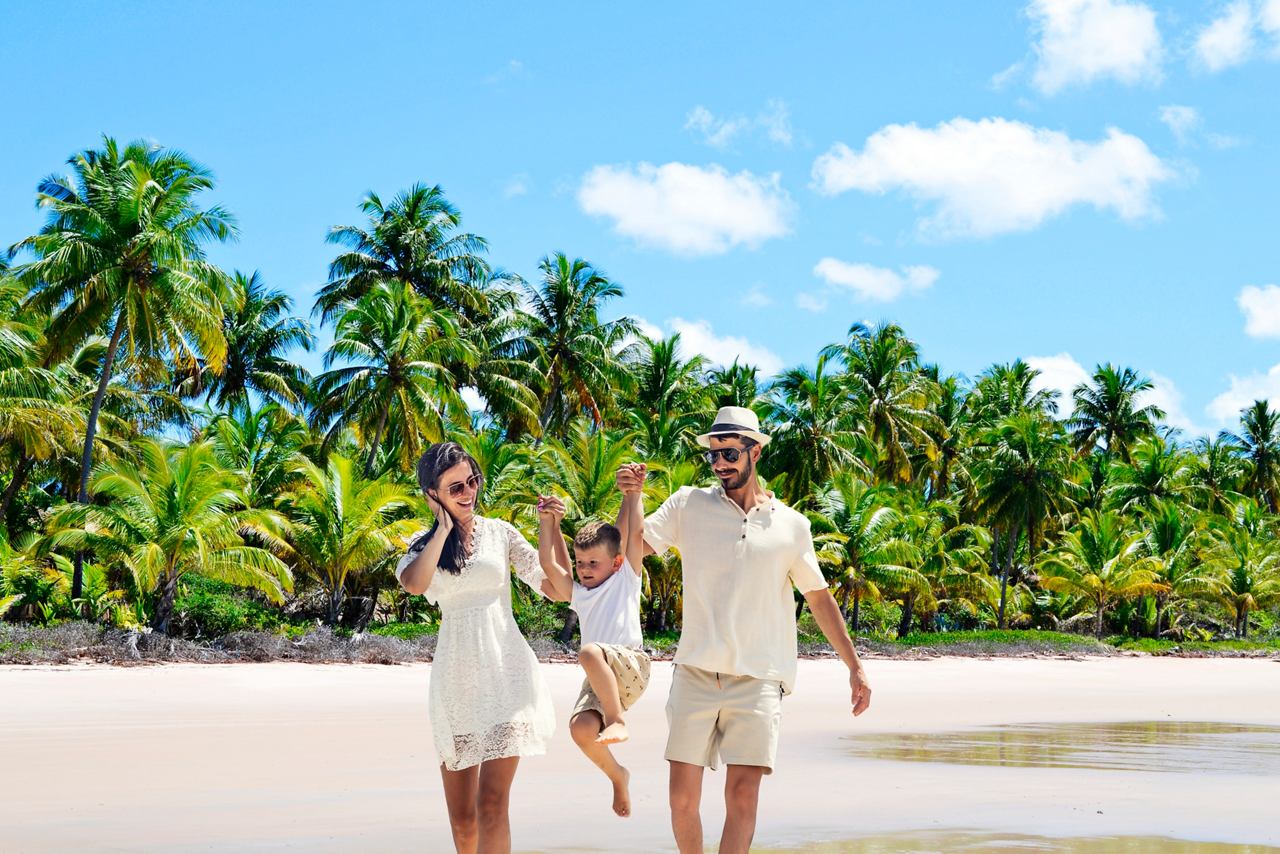 Famille heureuse sur la plage avec des palmiers et ciel bleu en arrière-plan | MSC Croisières