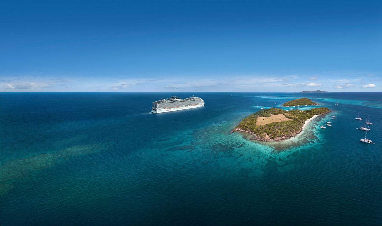Luftaufnahme des Kreuzfahrtschiffs MSC World Europa nahe einer tropischen Insel in der Karibik | MSC Cruises