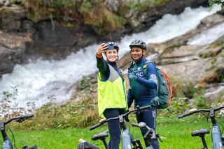 Happy team on a bike tour by a waterfall in Norway | MSC Cruises