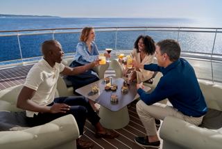 Un groupe partage boissons et snacks dans un espace extérieur avec vue sur la mer sur MSC World Europa | MSC Cruises