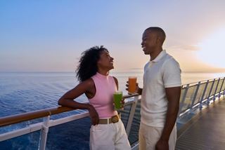 A couple enjoys drinks on the deck of a cruise ship with sunset over the sea | MSC Cruises