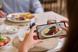 Guest aboard captures a gourmet dish in a stylish restaurant setting | MSC Cruises