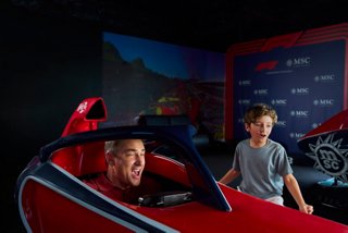 A child and adult enjoy the MSC Formula Racer simulator aboard MSC World Europa | MSC Cruises