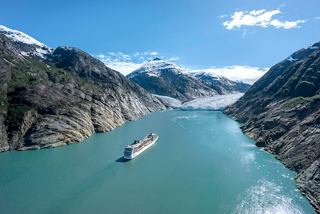 Cruise ship sails through a fjord with glacier and snowy mountains in a serene landscape | MSC Cruises