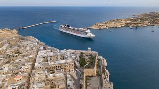 Cruise ship docked at a Mediterranean island port with a sweeping view of coastline and city | MSC Cruises