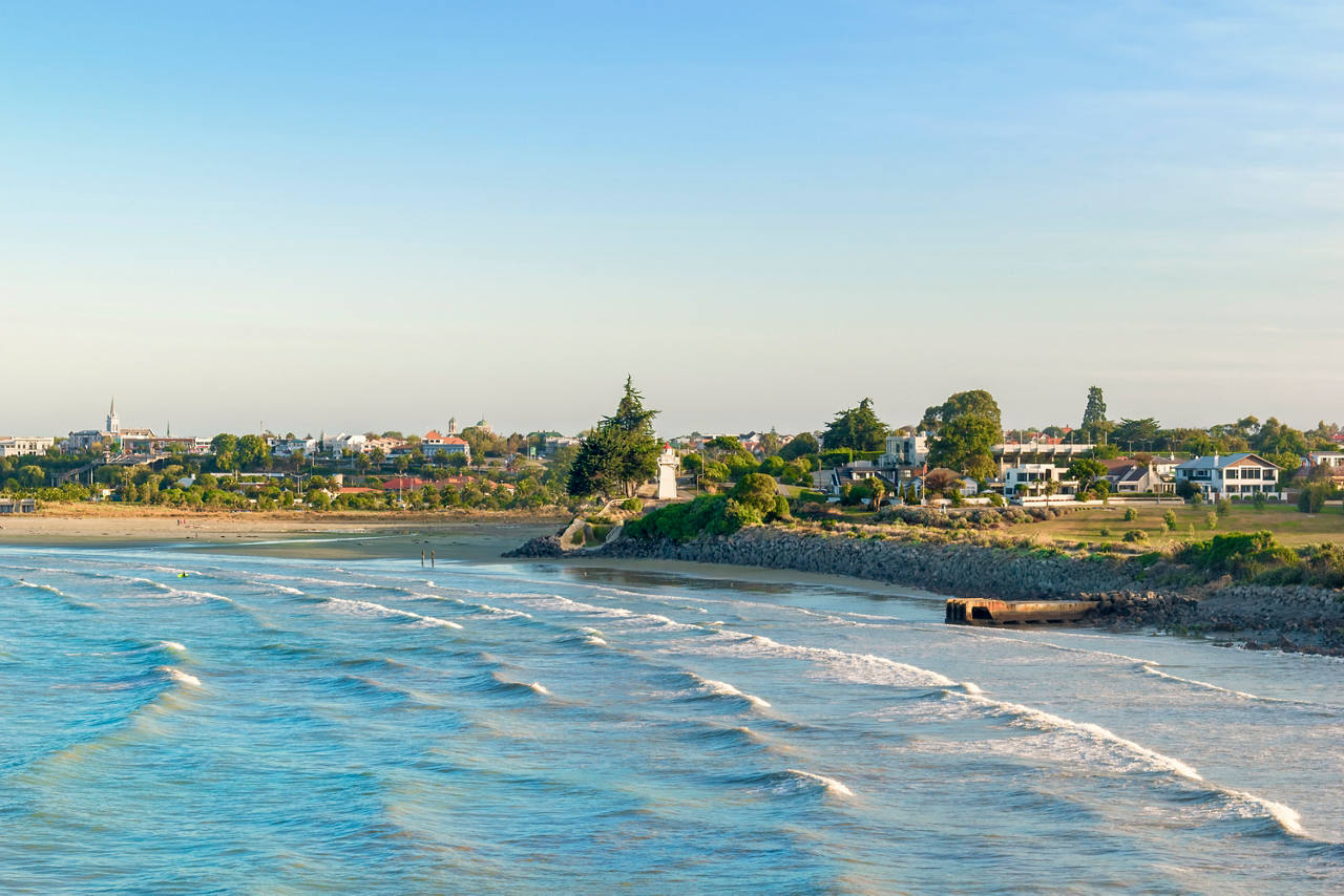 Sandy beach with houses and trees beside blue sea in Timaru, New Zealand | MSC Cruises