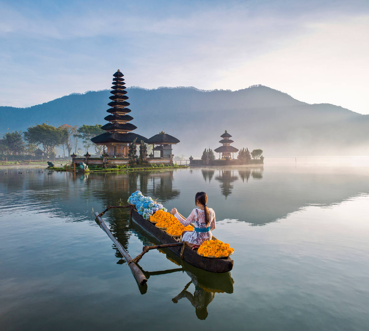 Una mujer rema en una barca cerca de un templo junto al lago en Bali rodeada de naturaleza | MSC Cruises