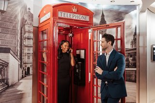 A couple interacts beside a classic red phone booth aboard a cruise ship | MSC Cruises