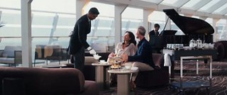 Opening shot of older couple being served champagne inside the Top Sail Lounge of MSC Yacht Club. 