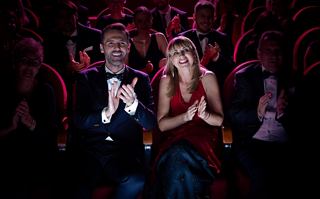 Ein Paar genießt einen lebhaften Abend mit Applaus in einer lebendigen Theateratmosphäre | MSC Cruises