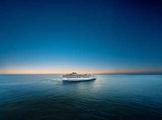 A cruise ship sails across calm waters under a clear blue sky at sunrise | MSC Cruises