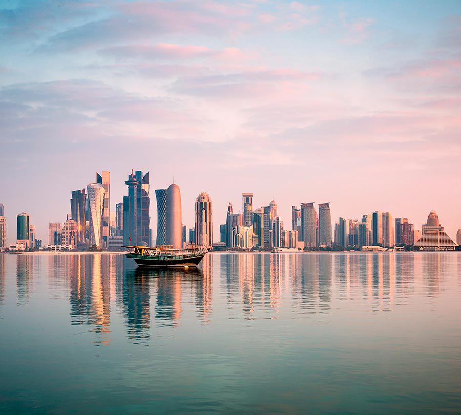 Silhouette moderner Gebäude spiegelt sich in ruhigem Wasser bei Sonnenuntergang | MSC Cruises