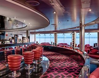 Ein stilvoller Lounge-Bereich mit lebhaften Sitzgelegenheiten und Panoramafenstern, die zur Entspannung und Geselligkeit einladen | MSC Cruises