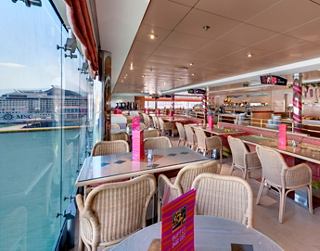 Ein einladender Speisebereich mit bequemen Sitzgelegenheiten und lebhafter Dekoration mit Blick auf das Wasser | MSC Cruises