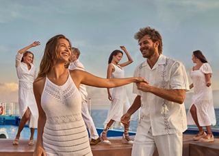 Un couple danse joyeusement ensemble lors d'une fête sur un bateau de croisière, entouré d'amis célébrant en arrière-plan | MSC Cruises