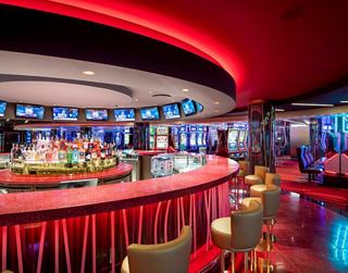 Modern bar with red accents and bright lights, perfect for entertainment and relaxation | MSC Cruises