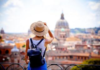 A woman with a hat enjoys the view of the dome of St. Peter's Basilica in Rome | MSC Cruises