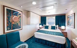 Une cabine confortable avec un lit double, une décoration élégante et de grandes fenêtres offrant une vue sur la mer | MSC Cruises