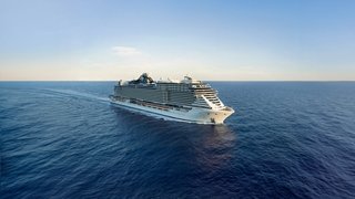 Un impresionante barco de crucero navega por aguas azules tranquilas bajo un cielo despejado | MSC Cruceros
