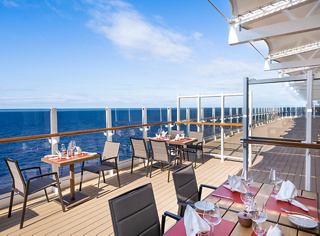 Un área de comedor serena con vista al océano, con mesas preparadas para una comida acogedora en un ambiente relajado | MSC Cruceros