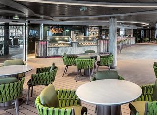 Un espacio brillante y acogedor con sillas y mesas verdes para momentos agradables con amigos | MSC Cruceros
