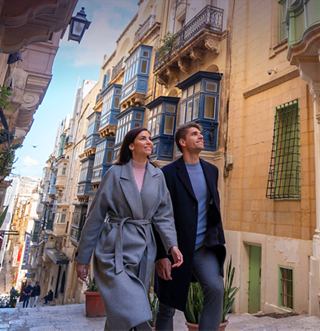 Two people walk along a vibrant street lined with colorful facades and balconies | MSC Cruises