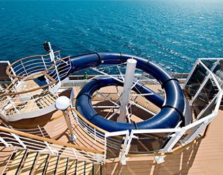 A thrilling water slide spirals down into a pool on a cruise ship deck with the sea in the background | MSC Cruises